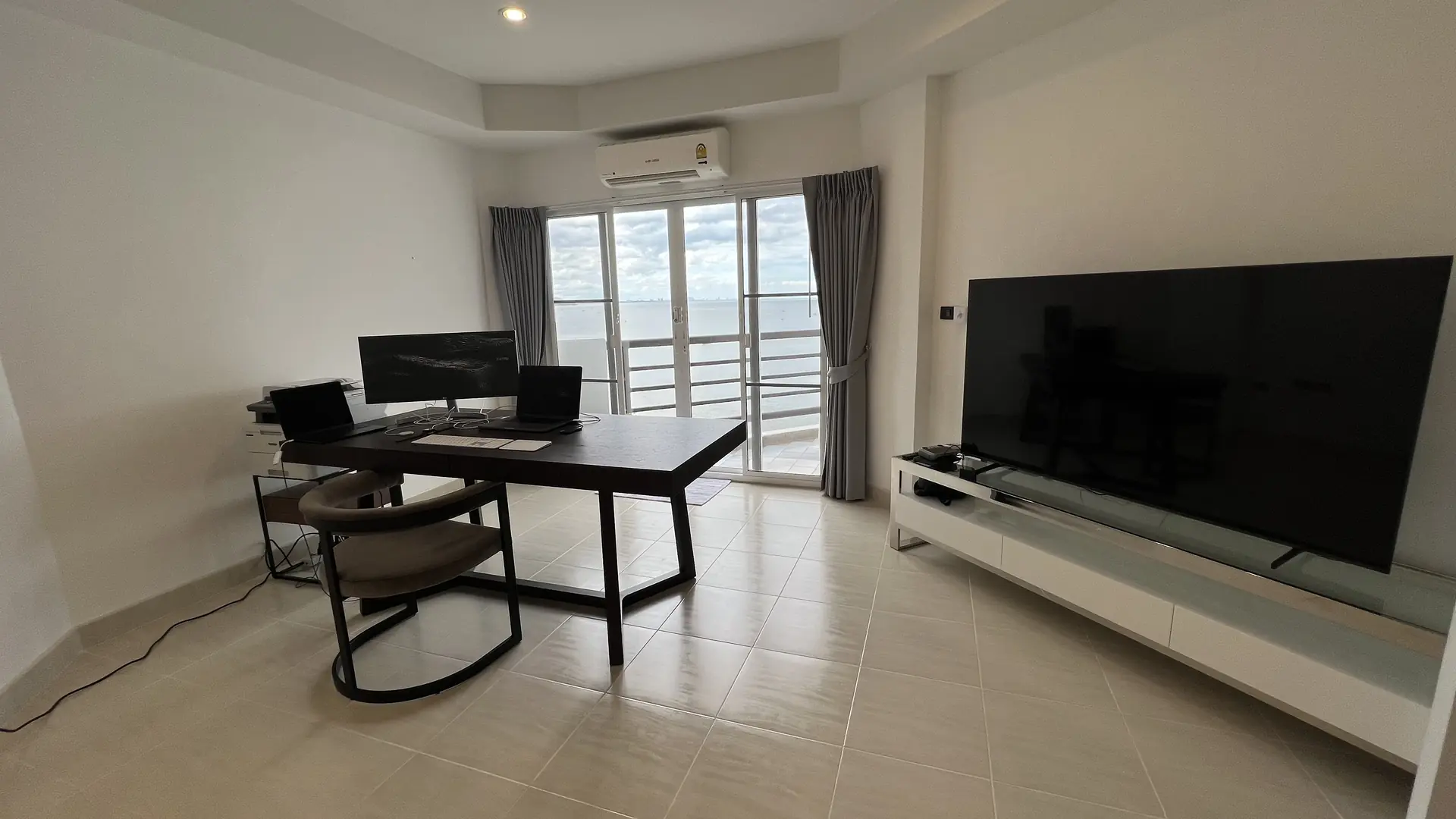 Dining table beside the balcony doors and wall-mounted TV