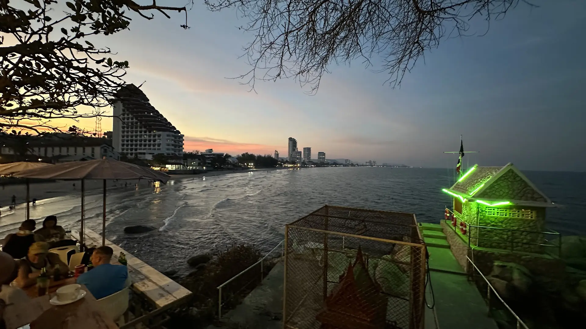 Seaside dinner tables at dusk with the coastline in view